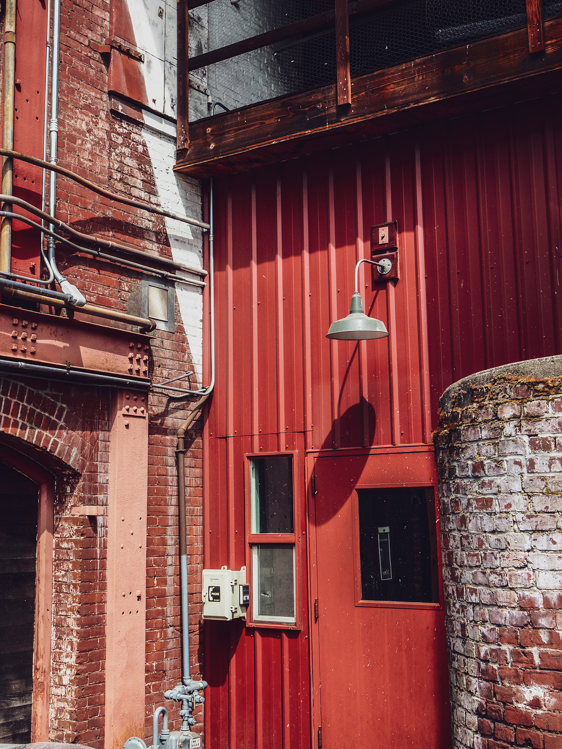 A mix of old wood, worn brick, red corrugated metal and orange girders