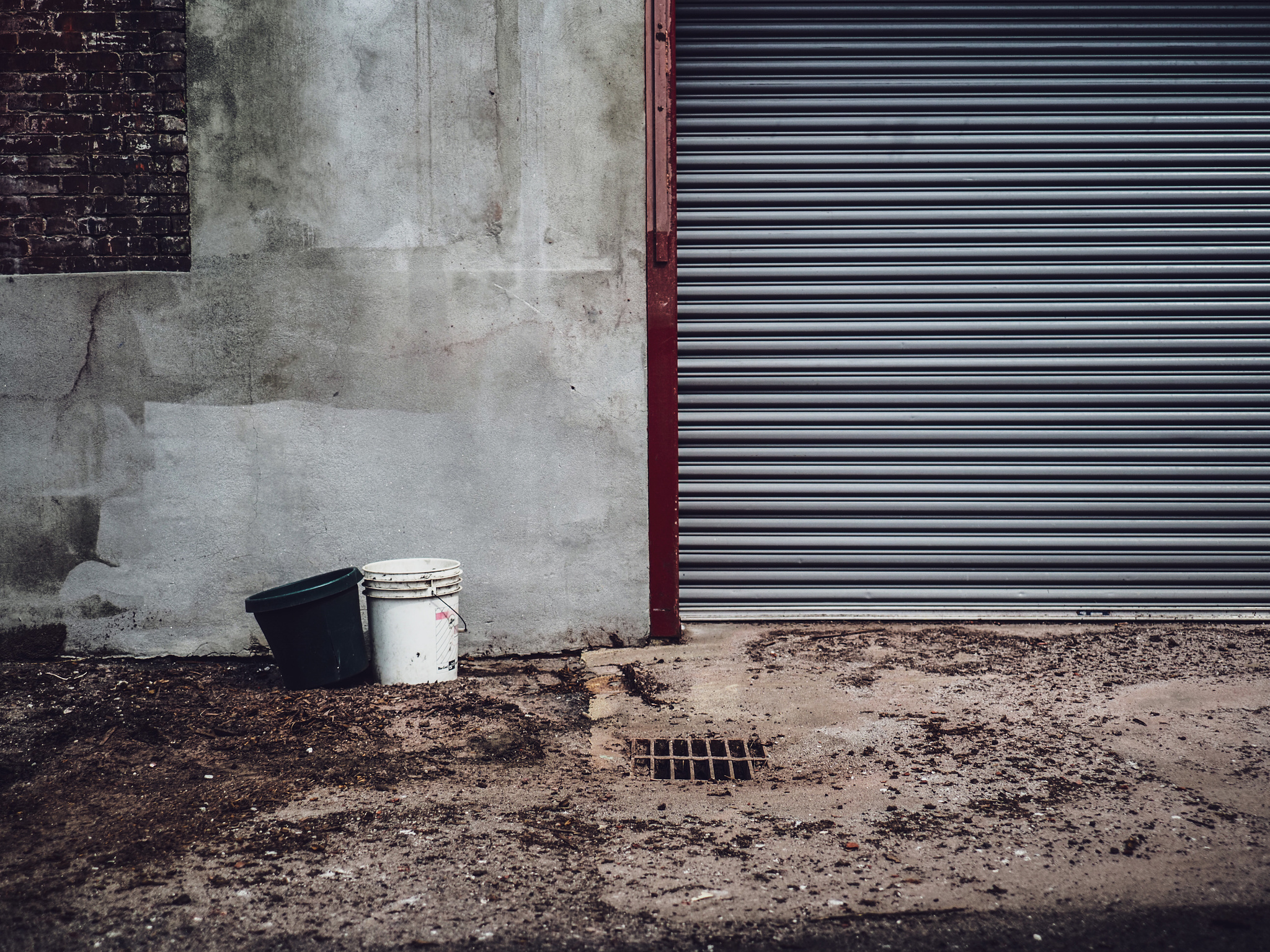 Two buckets and an steel door against a concrete wall