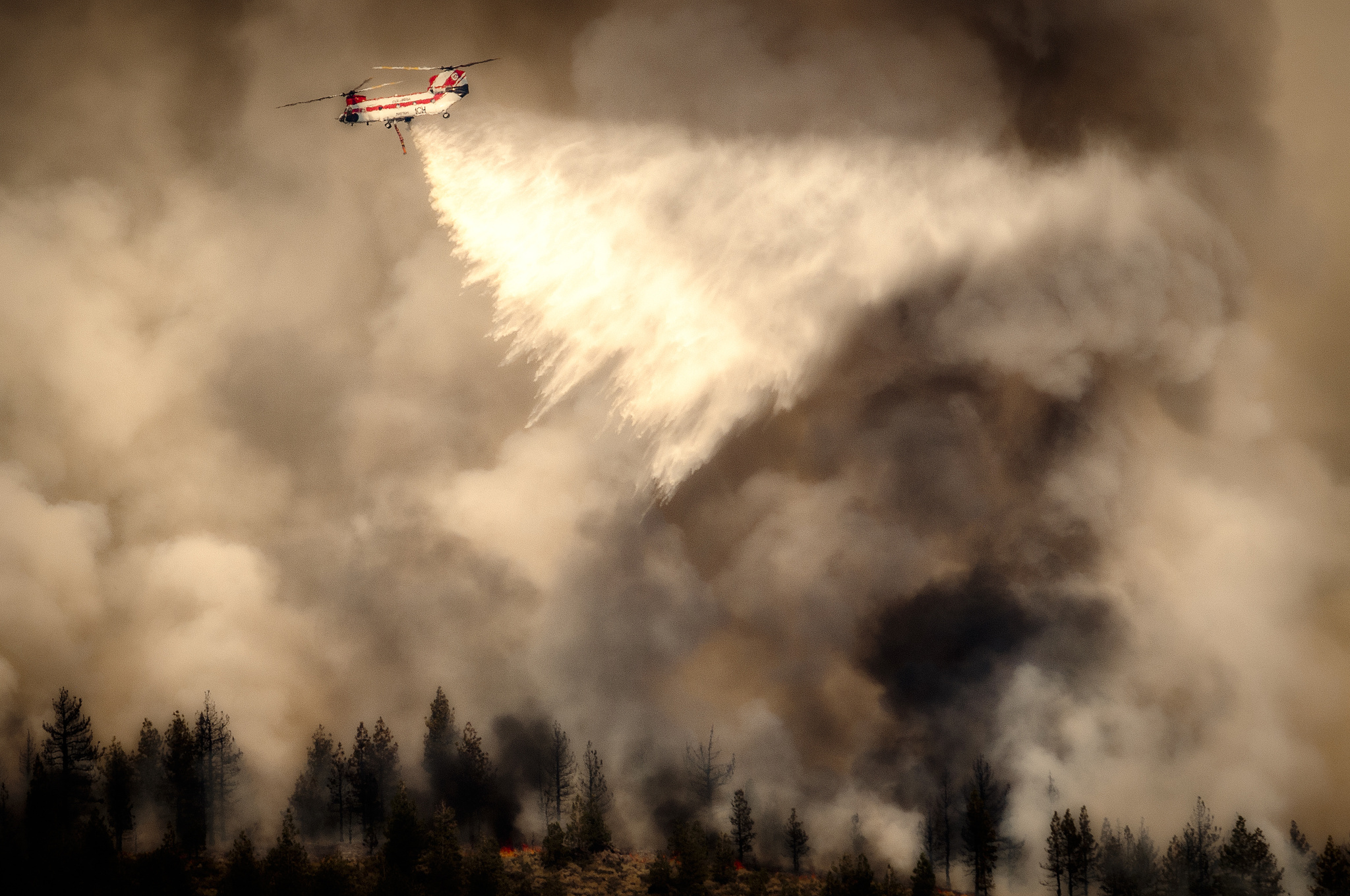 Fire Fighting helicopter droppping water on a fire in the hills.