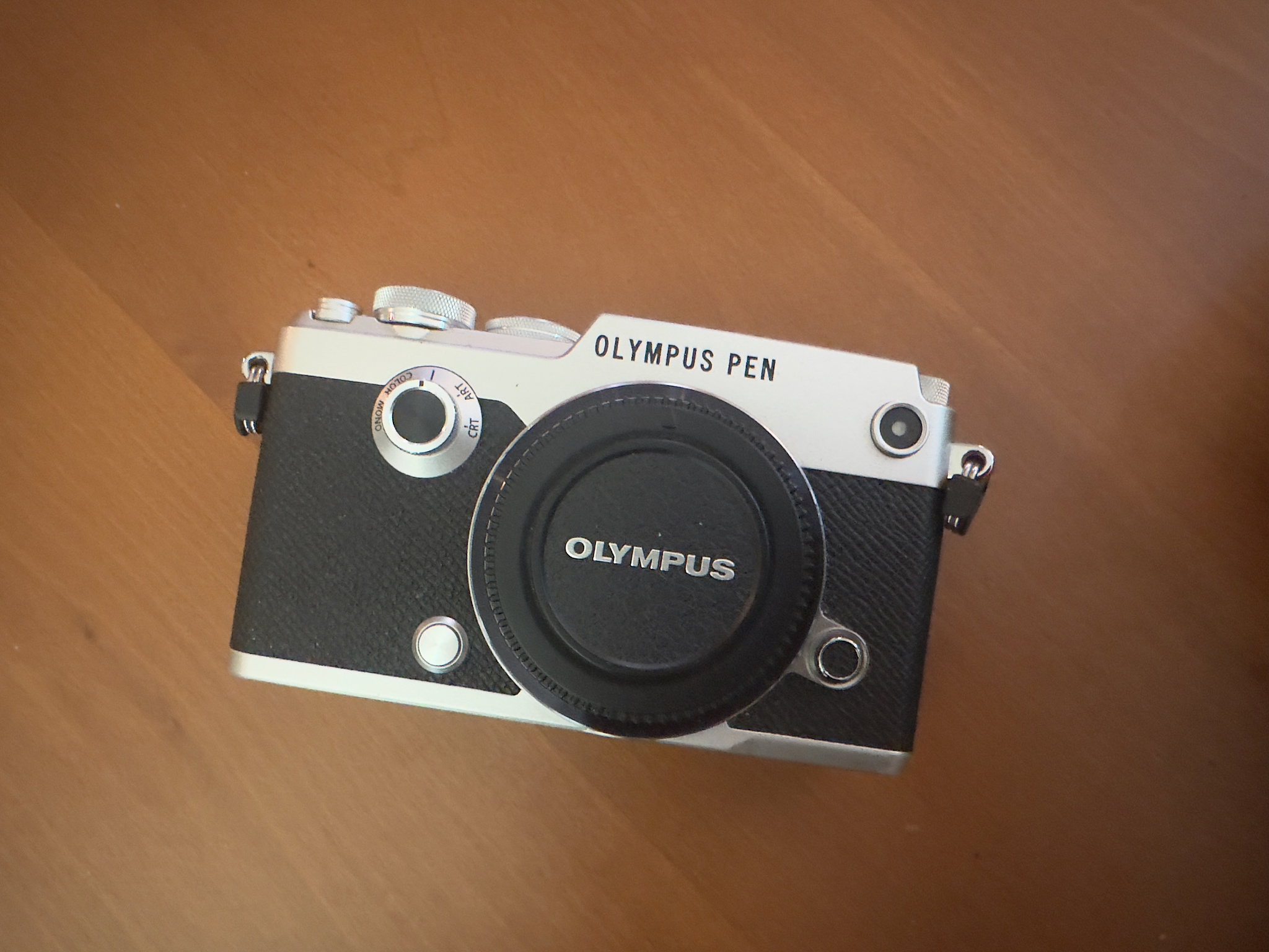 An Olympus Pen F digital camera with the body cap on 