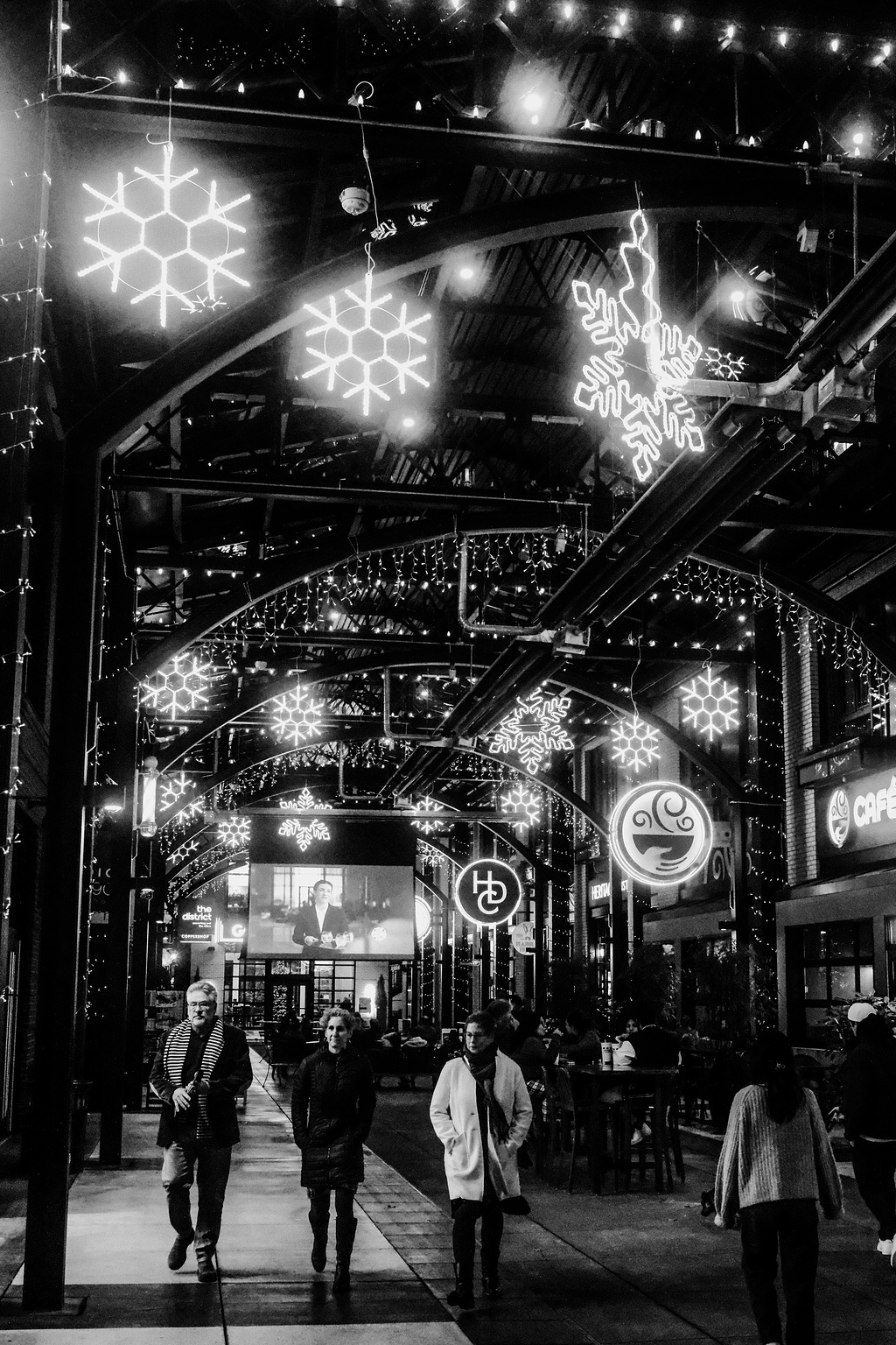 Monochrome. An outdoor mall lit with snowflake lights. 