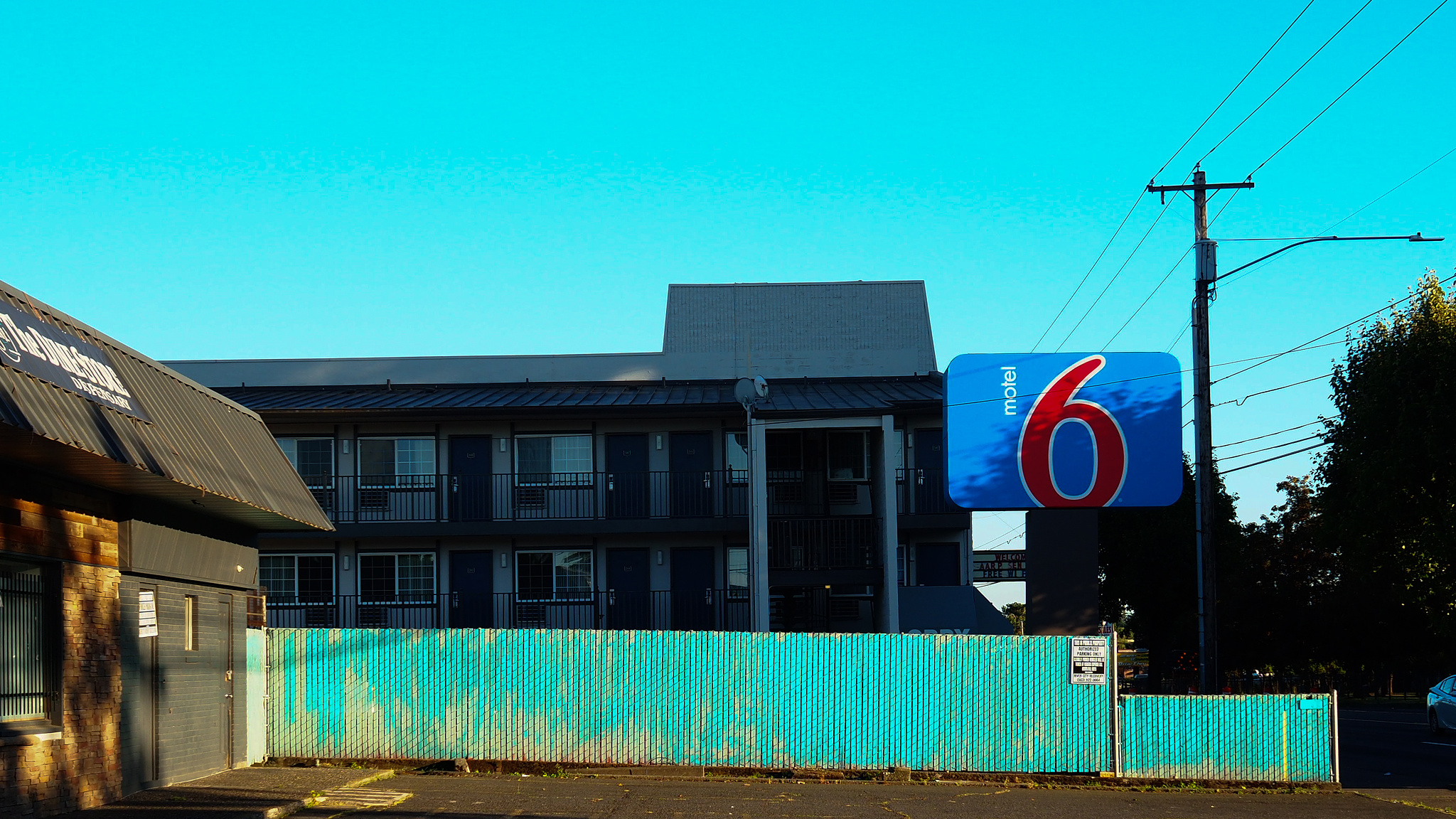 A Motel 6 sign behind an aquamarine fence