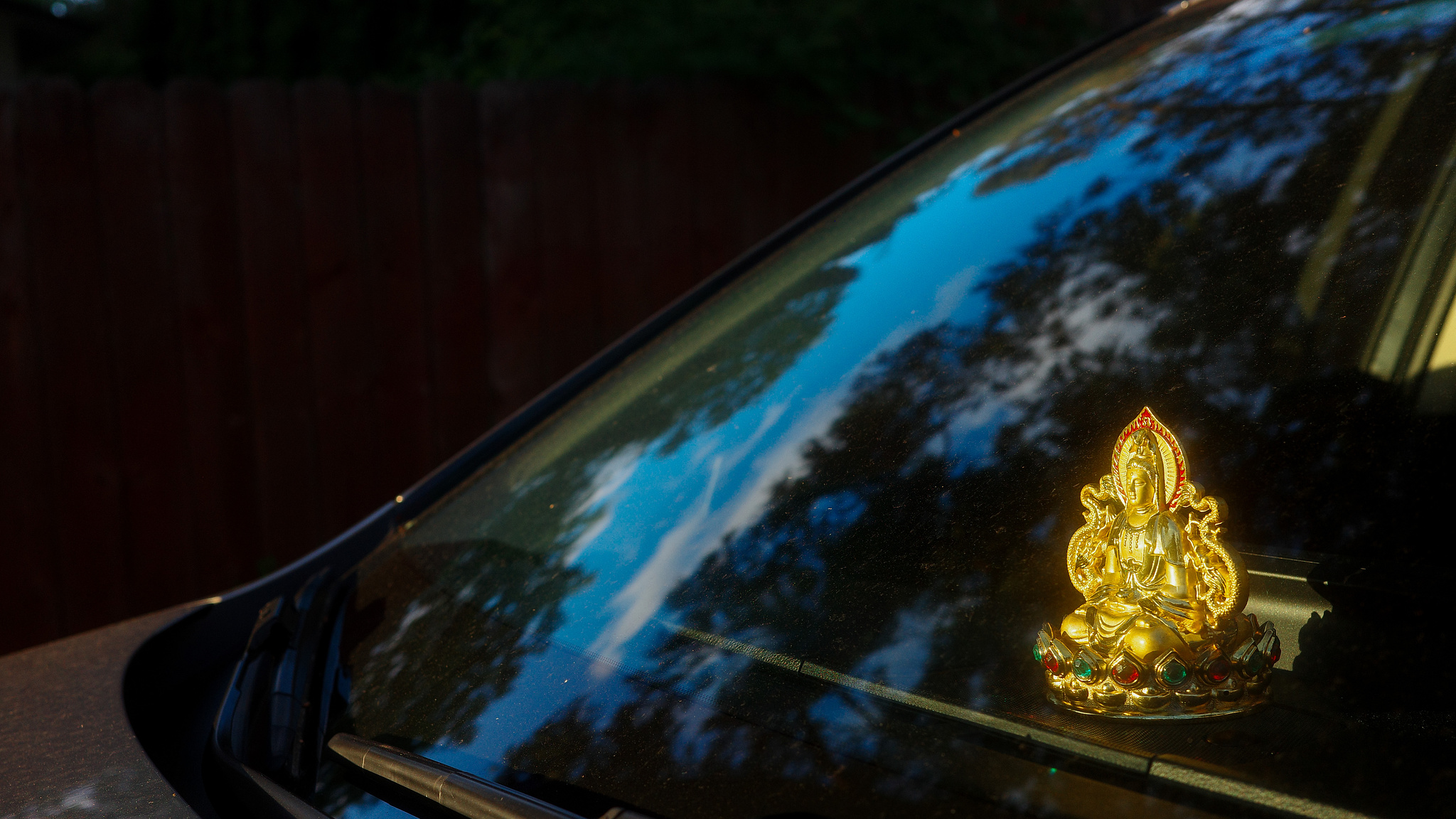 a golden dashboard buddha shining in the golden hour light