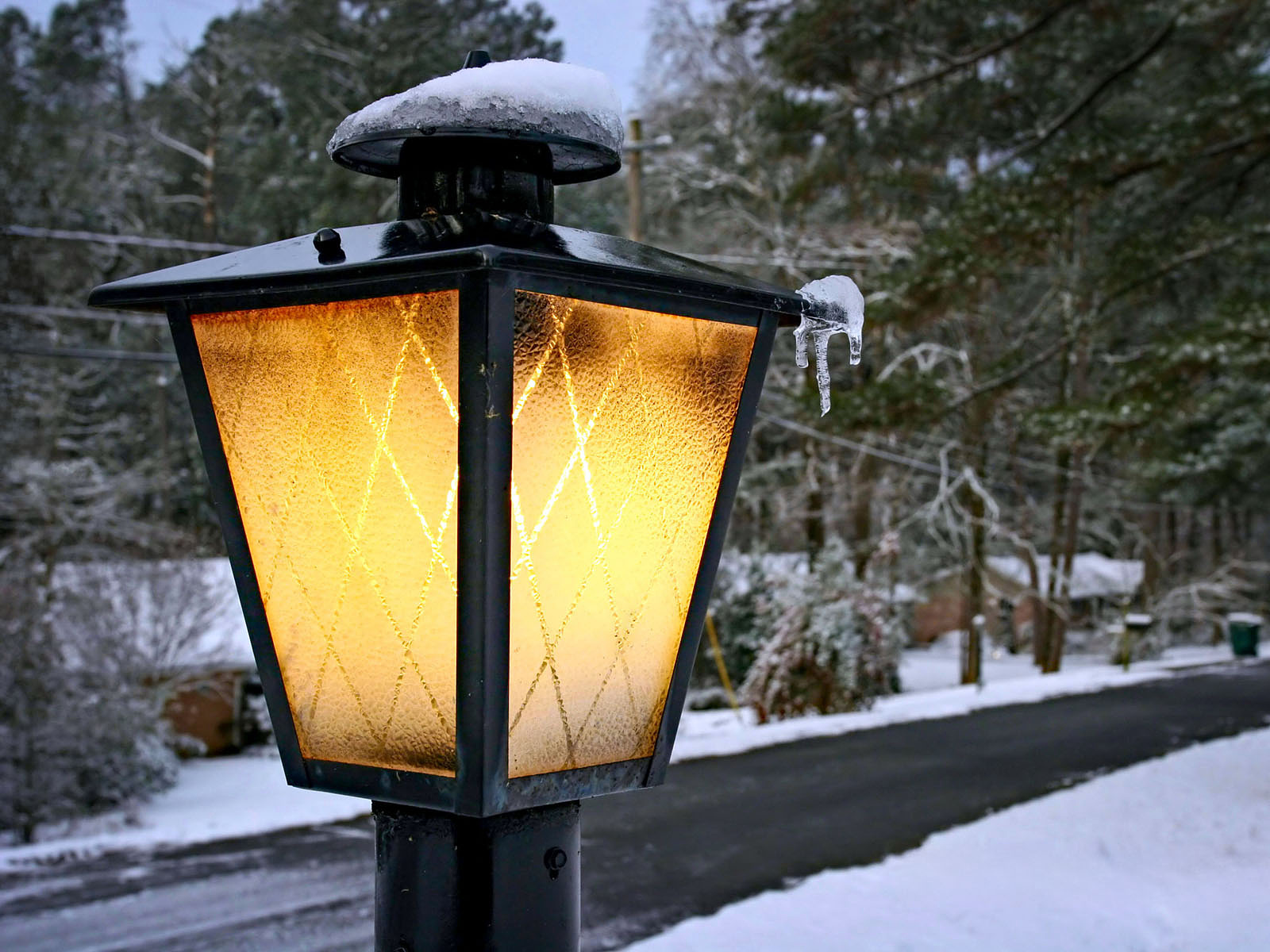 Glowing street lamp in a snowy neighborhood.