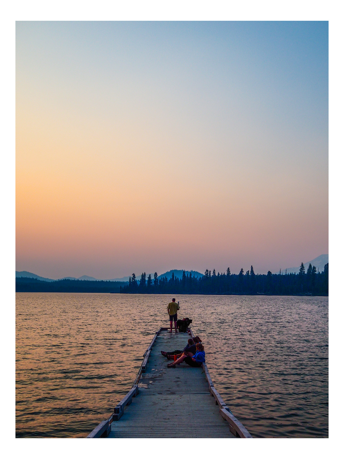 People on dock under a hazy, muted  sunset over a Central Oregon lake