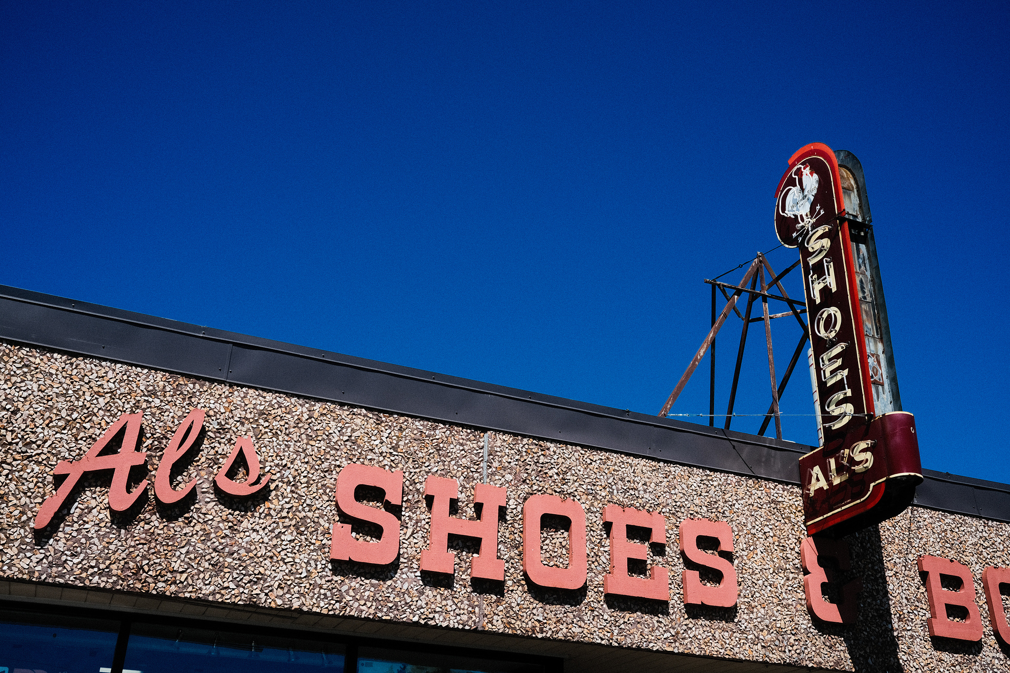 A store front with a red sign reading "Al's Shoes," with the same in a combination of script and western block type on the facade. 