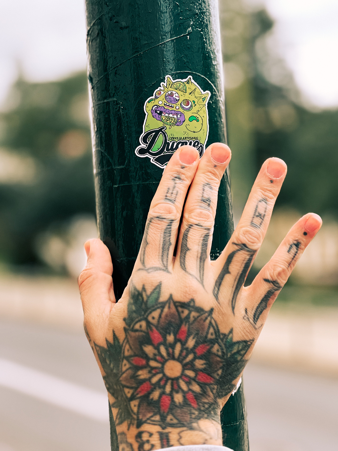 A tattooed hand placing a sticker. 