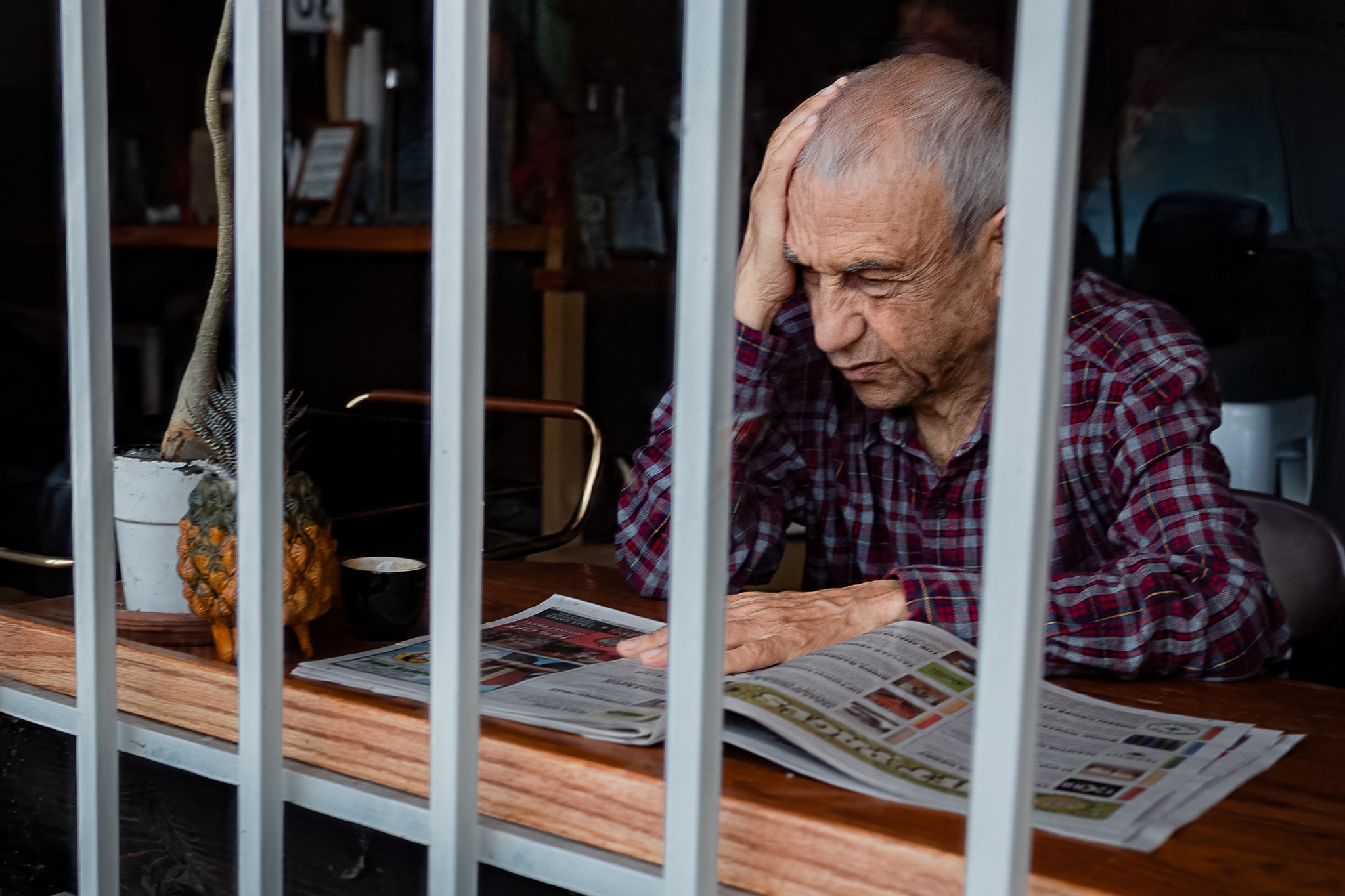 Photo of a man reading a newspaper throough the window