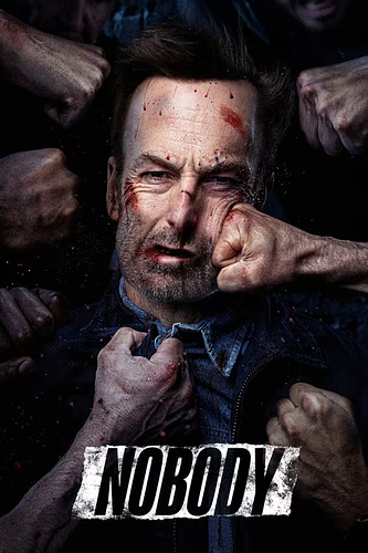 A close-up image of a man with a bruised and bloodied face, showing multiple cuts and scrapes, being punched repeatedly by several fists surrounding him. The man has short brown hair and a beard, and he wears a dark jacket over a blue shirt. His expression is one of pain and determination as he endures the assault. The background is dark, emphasizing the intensity of the scene. At the bottom of the image, the word "NOBODY" is prominently displayed in bold, distressed white capital letters against a black and white textured background. The overall tone is gritty and intense, suggesting a violent confrontation or struggle.
