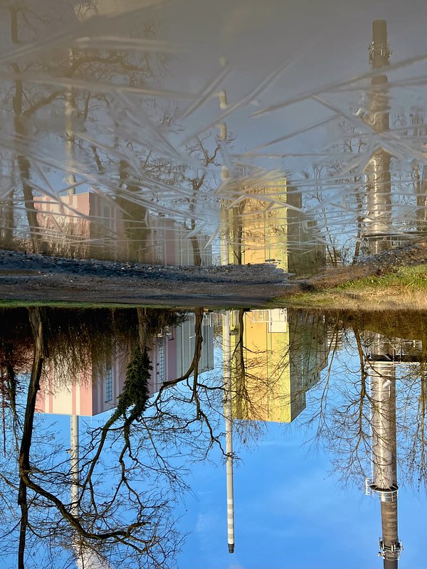 Three towers of a power station, reflection in puddle with a thin ice Layer. The picture is turned upside down.